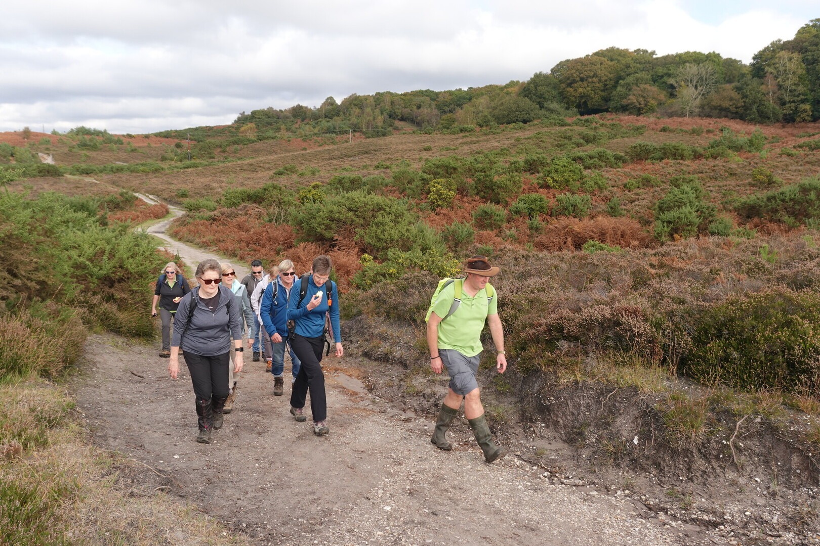 A person in a high vis vest leading a group up a hill