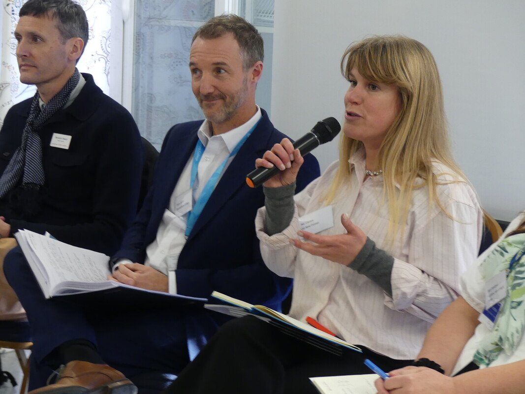 A woman holding a microphone speaking on a panel