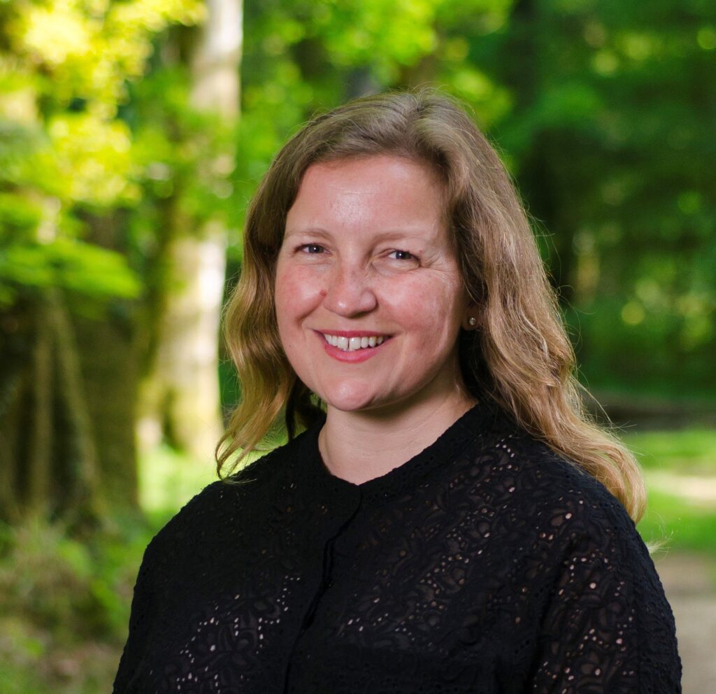 A woman wearing a black top standing in a forest