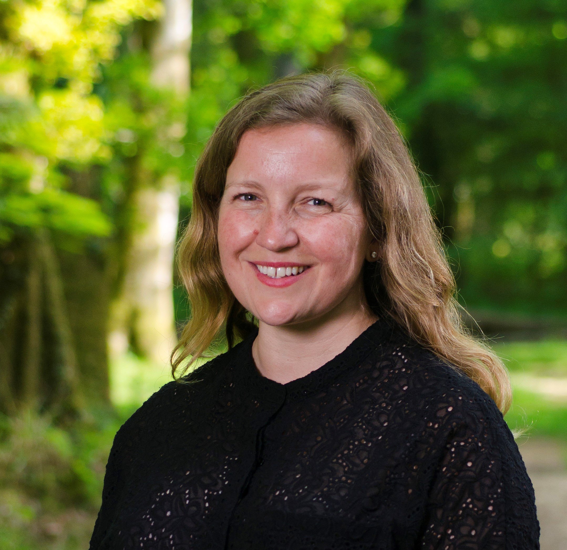 A woman wearing a black top standing in a forest