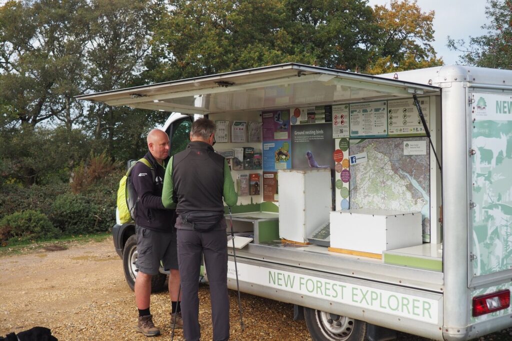 A New Forest NPA ranger engaging with a member of the public beside an NPA branded van